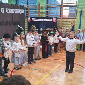 Grupa dzieci z instrumentami ustawione w szeregu, na środku chlopiec - dyrygent 