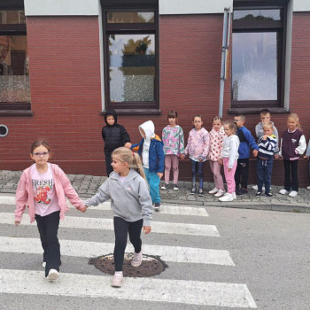 Dwoje uczniów przechodzi przez jezdnię 